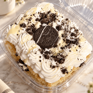 Oreo white chocolate milk cake topped with whipped cream, white chocolate and Oreo cookies